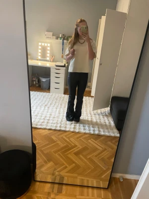 Svarta skinnbyxor - Säljer ett par svarta skinnbyxor med utsvängda ben. Byxorna har en tight passform upptill och släpper ut nedtill för en snygg siluett. Materialet är stretchigt och ger en cool look till outfiten. Perfekta för dig som gillar trendiga och bekväma byxor.