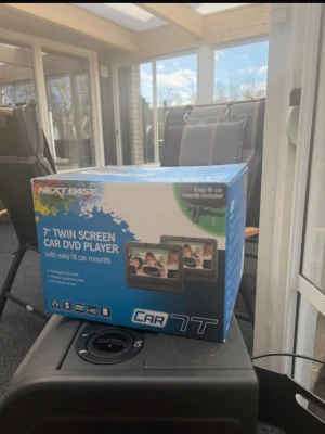 Nextbase 7" bil DVD-spelare med dubbla skärmar - Säljer en Nextbase 7-tums bil DVD-spelare med två skärmar. Perfekt för långa bilresor, enkel montering med medföljande fästen. Svart plastdesign och tydliga knappar på framsidan. Spelar DVD och har flera anslutningsmöjligheter.
