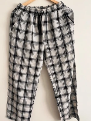 Pyjamas  - Snygga pyjamas med svartvitt rutmönster. Byxorna har två sidofickor fram och en bakficka. Perfekta för en chill och avslappnad stil. Materialet känns mjukt och bekvämt mot huden.