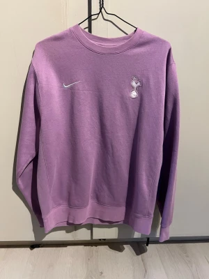 Lila Nike Tottenham crewneck - Säljer en lila crewneck från Nike med Tottenham Hotspur-logga på bröstet. Tröjan har rund halsringning, långa ärmar och är tillverkad i mjukt sweatshirtmaterial. Perfekt för dig som gillar sportig stil och vill visa ditt lag.