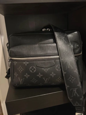 Louis Vuitton svart väska (äkta) - Säljer en svart axelväska från Louis Vuitton med klassiskt monogrammönster i grått. Den har inga större skador men är väll använd. Väskan har justerbar axelrem, silverfärgade dragkedjor och flera fack. Tillverkad i tåligt lädermaterial och har en stilren, köpt i Amsterdam 2020 köpt för 1460 euro kvitto finns !