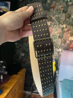 Brunt nitat bälte med metallspänne - Nytt och oanvänt. 105cm inklusive spänne. 80cm till mittenhålet. 48mm brett