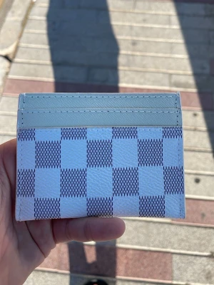 Vit och grå rutmönstrad kortplånbok - Kortplånbok i vitt och grått med klassiskt rutmönster. Tillverkad i slätt konstläder med flera kortfack. Snygg och stilren design som passar perfekt i fickan. Perfekt för dig som gillar minimalistiska accessoarer.