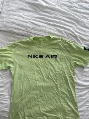 Nike Air t-shirt i ljusgrön - Fräsch ljusgrön t-shirt från Nike Air med svart tryck på bröstet. Klassisk rund hals och korta ärmar.