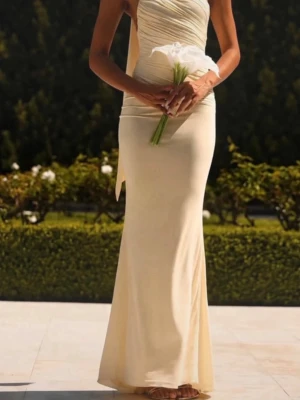 Ljusgul långklänning oneshoulder - Elegant långklänning i ljusgul färg med oneshoulder-design och draperad överdel. Klänningen har en figurnära passform och öppen rygg, vilket ger en stilren och lyxig look. Perfekt för speciella tillfällen där du vill sticka ut.