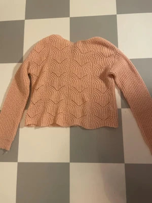 Ljusrosa stickad tröja med mönster - Söt ljusrosa stickad tröja med långt ärm och vågigt mönster framtill. Tröjan har en croppad passform och är ribbstickad på baksidan. Tröjan är i storlek 146/152 men passa på mig som vanligtvis bär storlek xs😳Pris kan diskuteras🥰