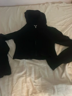 Svart hoodie med dragkedja - Säljer en svart hoodie med dragkedja framtill och huva. Hoodien har en enkel och clean design, perfekt att slänga på sig till jeans eller mjukisbyxor. Materialet känns mjukt och bekvämt. Passar dig som gillar en klassisk streetstil.