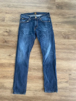 Lee jeans – klassisk blå tvätt, slim fit, stl S/M - Säljer ett par snygga Lee-jeans i klassisk blå tvätt med smal passform. Bekväma och stilrena jeans som passar lika bra till vardag som till en mer uppklädd look.  Byxorna är i bra begagnat skick och har gott om användning kvar.