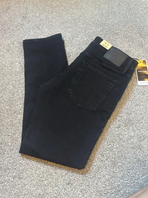 Jack & Jones - Snygga svarta slim fit jeans från Jack & Jones med klassisk femficksdesign och svarta sömmar. Jeansen har en stilren look och är tillverkade i ett stretchigt material för extra komfort. Perfekta till en avslappnad eller trendig outfit.