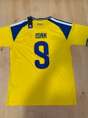 Isak #9 – Sverige Hemma (storlek M) - Isak #9-tryck. Sverige Hemma (gul). Storlek M. Helt ny och aldrig använd. Skickas snabbt 🚚💨  Mått (M): Halvt bröstmått 53 cm • Längd 74 cm • Ärmbredd 23 cm • Axelbredd 44 cm • Ärmlängd 40 cm • Manschett 19 cm.  🔥 Fan Edition – normal passform. 🇸🇪 Sverige landslag.  📩 Frågor eller prisförslag? Skicka gärna ett meddelande! 🛍 Bundle-rabatt upp till 20% 💰 📦 Skickas samma eller nästa dag 🌟