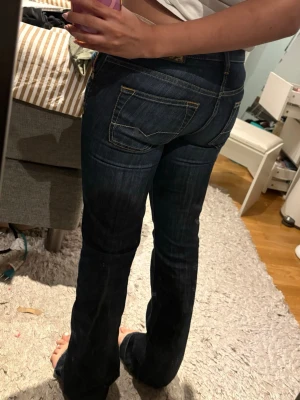 Mörkblå vintage lågmidjade bootcut jeans - Midjemått: 38cm innerbenslängd: 80cm Pris går absolut att diskuteras❤️ Säljer ett par mörkblå bootcut jeans med snygga kontrastsömmar och låg midja. Jeansen har klassiska fem fickor och slitningar framtill för en cool look. Perfekt för dig som gillar en avslappnad men trendig y2k 2000s stil.