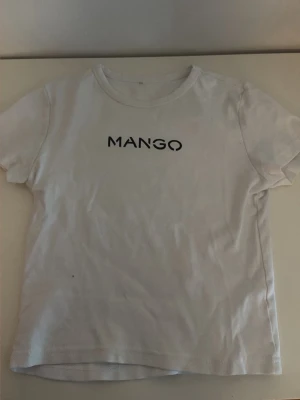 Vit t-shirt  - Klassisk vit t-shirt från svart logotyp tryckt på bröstet. T-shirten har rund halsringning och korta ärmar. Tillverkad i mjuk bomull för en bekväm känsla och enkel stil.