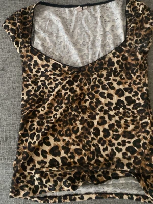 Leopardmönstrad topp från Nelly - Snygg leopardmönstrad topp från Nelly med v-ringning och korta ärmar. Tunn och lätt i materialet, perfekt för att sticka ut med ett djurmönster. Passar dig som gillar trendiga och djärva plagg.