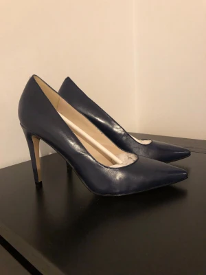 Mörkblå klassiska pumps i skinn - Snygga mörkblå pumps med spetsig tå och hög klack. Skorna är tillverkade i slätt skinn och har en elegant, tidlös design. Perfekta för dig som vill ha en stilren och chic look.