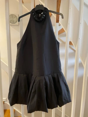 Svart klänning H&M Edition grym klänning - Svart klänning med stenar i halsen. Storlek L rymlig i storleken.  Använd 1 gång så nyskick.  Eftertraktad H&M EDITION.  Längd ca 96 cm
