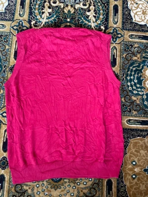 Rosa stickad väst från Chaps - Snygg rosa stickad väst från Chaps med v-ringad hals. Perfekt att slänga över en skjorta eller t-shirt för en chill och stilren look. Ribbad kant nedtill och runt halsen ger en klassisk touch.