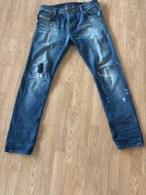 Blå slitna jeans från Diesel - Ricktigt feta ripped jeans från Diesel. Modellen är lite rakare. De är i storlek 32/32. Perfekt för dig som vill ha en lite mer relaxed look.                                Skriv vid flera frågor!!
