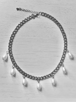 Kedjehalsband med droppformade pärlor - Snyggt halsband i silverfärgad rostfritt med grov kedja och sju vita, droppformade pärlor som hänger som detaljer. Justerbar längd med förlängningskedja. Perfekt accessoar för att lyfta din outfit.