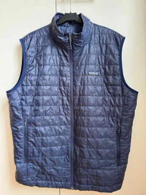 Patagonia Nano Puff Vest - Jag säljer min blå Patagoniaväst då den blivit för stor för mig. Den är sparsamt använd och inga synliga fel eller slitage. Den fungerar bra som både ytterplagg och förstärkningsplagg.