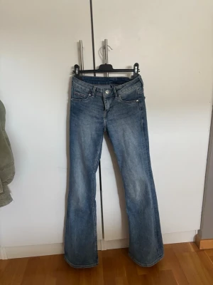 Blå bootcut jeans med låg midja - Snygga blå bootcut jeans med låg midja.  Jeansen har en lätt tvättad look och subtila slitningar framtill. 