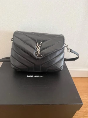 YSL LOULOU - Väskan är läder och quiltad i chevronmönster och har justerbar axelrem i läder och metall. Kommer med box, påse, kort och dustbag. Perfekt för dig som vill ha en lyxig  accessoar. 20x14x7,5