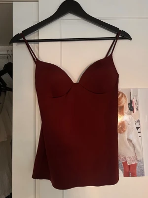 Vinröd body liknande topp Zara - Snygg vinröd linnetopp med tunna axelband och vadderade kupor från Zara💗 Toppen har en figurnära passform och är tillverkad i ett slätt, mjukt material som ger en elegant look. Perfekt att styla med jeans eller kjol för fest eller bara allmänt en snygg outfit. 