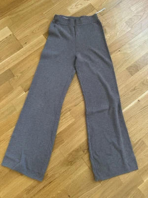 Grå mjukisbyxor från H&M - Mysiga grå mjukisbyxor från H&M med bred resår i midjan och raka, vida ben. Tillverkade i en mjuk blandning av polyester och viskos som känns skön mot huden. Perfekta för chill dagar hemma eller när du vill ha en avslappnad look.