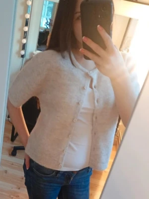 Ljusgrå kortärmad kofta med knappar - Superfin kofta med korta ärmar och rund hals. Koftan har en rak passform och kan både användas öppen och stängd. perfekt att slänga över en t-shirt eller linne storlek finns på bilden.. Passar till jeans eller kjol för en chill och söt look 💗☺️