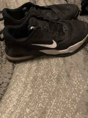 Svarta Nike sneakers med vit sula - Svarta Nike sneakers med vit sula och klassisk vit swoosh på sidan. Ovandelen är i meshmaterial för bra andningsförmåga och skon har en låg profil. Yttersulan är svart med bra grepp. Perfekta för en sportig och stilren look.