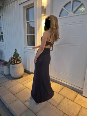 Mörkblå lång klänning med spetsdetaljer - Säljer min balklänning, använd 1 gång, köptes för 1600kr från Zapaka. Bra materiel, inbygg bh. Klänningen är öppen i ryggen med en lång slits. Pris kan diskuteras