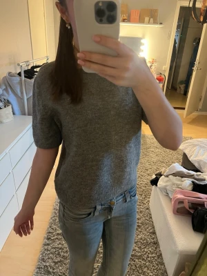 Grå stickad Tshirt - Mysig grå stickad tshirt med rund halsringning och korta ärmar. Från h&m i storlek M. Knappt använd. Perfekt till jeans eller kjol för en enkel men snygg look. Ribbad kant nedtill och vid ärmslut för extra detalj. Skriv om du undrar något💕