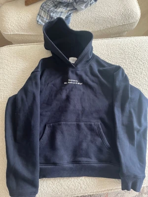 Mörkblå hoodie Stockholm tryck - Snygg mörkblå hoodie från Notre succès med vit text på bröstet och stort Stockholm-tryck på ryggen. Klassisk känguruficka framtill och huva. Perfekt för dig som gillar streetwear och vill ha en stilren look. Mjuk bomullskänsla.