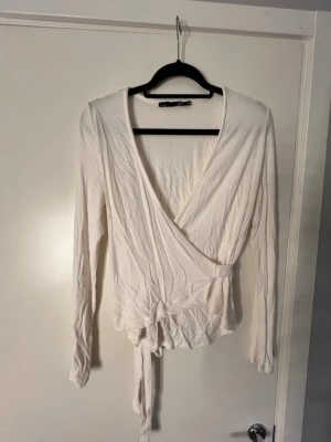 Vit omlottopp med knytband - Säljer en vit omlottopp med långa ärmar och knytband i midjan. Storlek XS från lager 157. Perfekt för dig som gillar en enkel men snygg stil. Skriv om du undrar något💕