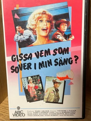 VHS: Gissa vem som sover i min säng? - Säljer en VHS-film med titeln 'Gissa vem som sover i min säng?'. Omslaget har färgglad design med bilder från filmen och text på svenska. Filmen är en komedi, svensktextad och har en speltid på 74 minuter. Perfekt för dig som samlar på retrofilmer eller gillar klassiska komedier.