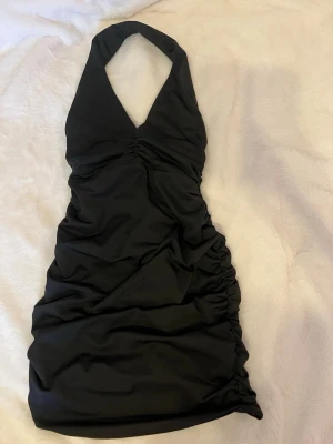 Svart halterneck klänning - Svart miniklänning med halterneck och rynkade detaljer längs hela klänningen