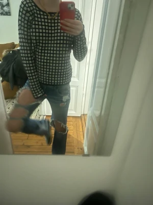 Svartvitrutig långärmad topp - Trendig långärmad topp med svart och vitt rutmönster. Modellen är figurnära med rund halsringning och stretchigt material som sitter snyggt på kroppen. Perfekt för dig som gillar grafiska mönster och en clean look.