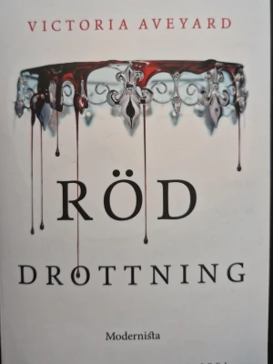 Röd drottning av Victoria Aveyard - Röd drottning är en fantasyroman av Victoria Aveyard. Omslaget är vitt med en silverkrona som droppar blod, vilket ger en dramatisk känsla. Boken handlar om Mare Barrow i en värld där blod avgör makt och status. Perfekt för dig som gillar spänning, magi och maktkamp. PRIS KAN DISKUTERAS, TVEKA INTE ATT FRÅGA!