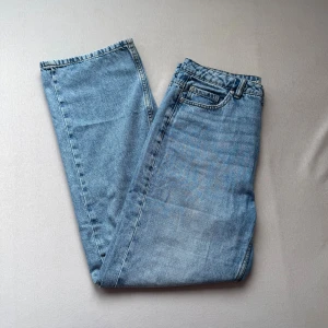 Blå raka jeans i klassisk modell - Säljer ett par blå jeans med rak passform och klassisk femficksdesign. Jeansen har normalhög midja och är tillverkade i denim. Perfekta för en avslappnad och tidlös stil.