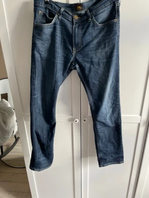 Mörkblå jeans från Lee - Snygga mörkblå jeans från Lee med klassisk femficksmodell. Jeansen har raka ben och är tillverkade i ett slitstarkt denim w33 l30