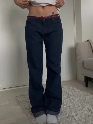 Mörkblå raka jeans - Säljer ett par mörkblå jeans med rak lite baggy passform och klassisk femficksdesign. Jeansen är lite stor på mig där av har jag ett skärp. Tillverkade i ett kraftigare denimtyg. Skriv för mått