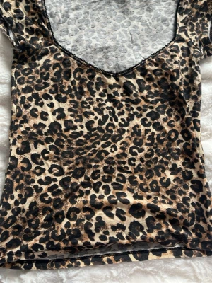 Leopardmönstrad topp med v-ringning - Snygg leopardmönstrad topp med v-ringning och korta ärmar. Tunn och stretchig, perfekt för dig som vill sticka ut. Djurmönstret går i beige, brunt och svart. Passar till både jeans och kjol för en trendig look.