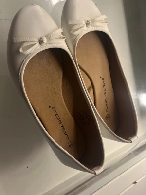 Vita ballerinaskor med rosett - Säljer ett par klassiska vita ballerinaskor från Claudia Ghizzani. Skorna är använda en gång därför i bra skick köpt för några hundra 