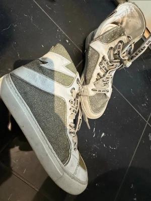 Zadig Voltaire höga sneakers storlek 36 - Snygga höga sneakers från Zadig & Voltaire. Skorna har en unik design med detaljer som ger dem en speciell stil. Perfekt för att piffa upp vilken outfit som helst! Använda men går att snygga till dem med en tvätt. Storlek 36 Dyra i inköpspris