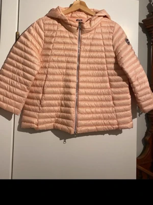 Ljusrosa lättviktsjacka med huva - Snygg ljusrosa jacka från Colmar med quiltad design och stor huva. Jackan har trekvartsärmar, dragkedja framtill fickor med dragkedja samt innerfickor 