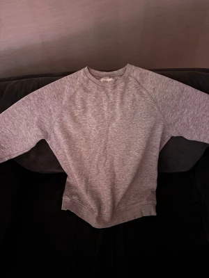 Grå sweatshirt från Pier One - En stilren grå sweatshirt från Pier One i mjukt bomullsmaterial. Tröjan har rund halsringning, långa ärmar och ribbade muddar vid ärmslut och nederkant. Perfekt för en avslappnad och enkel look.