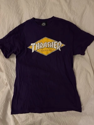 Lila Thrasher t-shirt med tryck - Säljer en lila Thrasher t-shirt med stort gult och vitt logotryck på bröstet. Så cool men har ändrat stil så den passar inte mig längre… Använd några få gånger