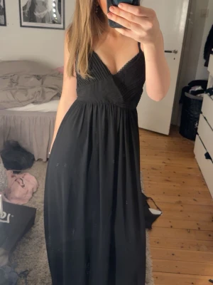 Svart långklänning med öppen rygg - Säljer en svart långklänning med smala axelband och djup v-ringning 
