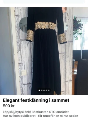 Svart långklänning i sammet med guld - Elegant svart långklänning i mjuk sammet med guldiga broderade detaljer vid midjan, ärmsluten, halsringningen och nederkanten. Klänningen har långa ärmar och medföljer en matchande sjal med guldkant. Perfekt för speciella tillfällen.