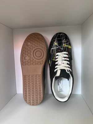 Maison Margiela skor - Maison Margiela “Paint Splash” sneakers i svart med färgstänk 🎨 ett stilrent och unikt par som passar perfekt till sommaren ☀️👟storlek 43! Skorna är endast änvänt 1 gång, alltså i toppskick ✨ Observera att ingen box ingår, det är endast skorna som säljs 📦 Bekväma och enkla att matcha med olika outfits 👌 Skicka meddelande för mer information och om ni är intresserade eller om ni vill ha fler bilder 🙂