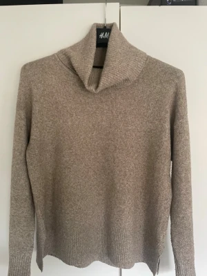 Beige/brun stickad polotröja  - Beige/ brun stickad polotröja med polokrage och ribbade muddar vid ärmslut och nederkant och små slitsar i sidorna.